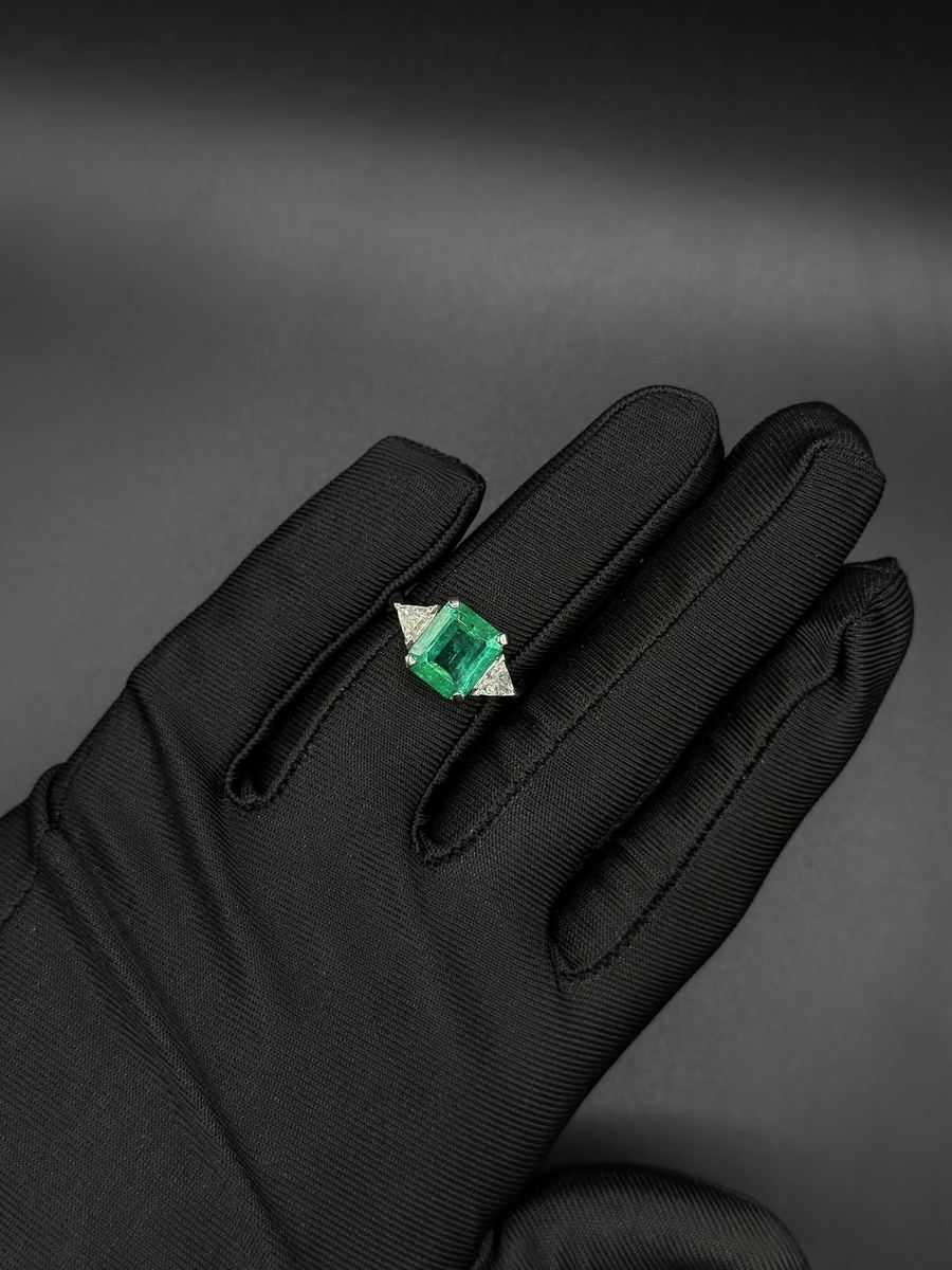 Anello con smeraldo taglio smeraldo e due diamanti trilioni